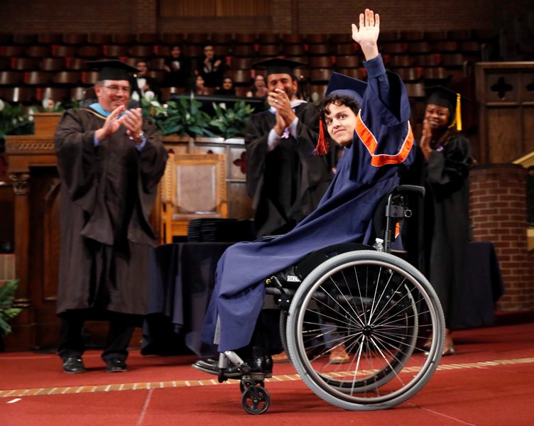 In this Monday, June 13, 2016 photo, Jonathan Annicks waves to a cheering crowd as he graduates from high school in Chicago.