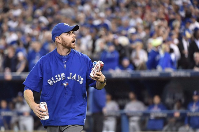 A Rogers Centre employee picks up beer cans thrown on the field by fans during seventh inning game five American League Division Series baseball action between the Texas Rangers and the Toronto Blue Jays in Toronto on Wednesday, Oct. 14, 2015.