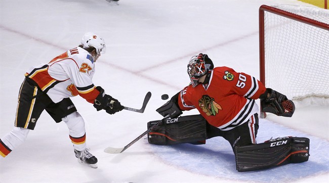 Chicago Blackhawks goalie Corey Crawford (50) makes a save on a shot from Calgary Flames' Sean Monahan during the first period of an NHL hockey game, Monday, Oct. 24, 2016, in Chicago. 