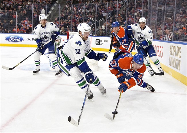 Vancouver Canucks' Henrik Sedin (33) and Edmonton Oilers' Connor McDavid (97) battle for the puck during first period NHL pre-season action in Edmonton, Alta., on Saturday October 8, 2016.