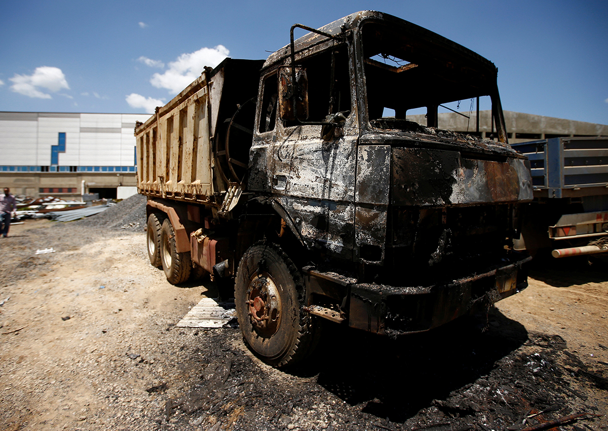 People walk near a torched truck in the compound of a textile factory damaged by protests in the town of Sebeta, Oromia region, Ethiopia, October 8, 2016. 