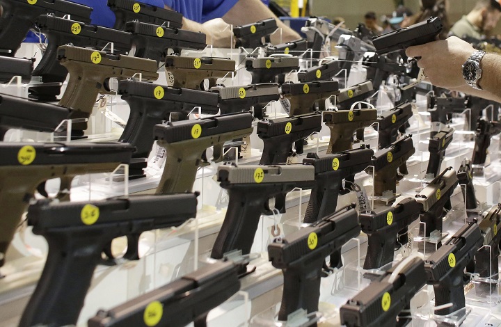 A customer looks at a pistol at a vendor's display at a gun show held by Florida Gun Shows in Miami on Saturday, Jan. 9, 2016. 