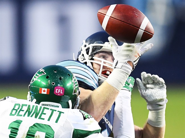 Toronto Argonauts' Brian Jones is hit as he attempts to catch a pass by Saskatchewan Roughriders' Fred Bennett during second half CFL action in Toronto, Saturday, October 15, 2016.