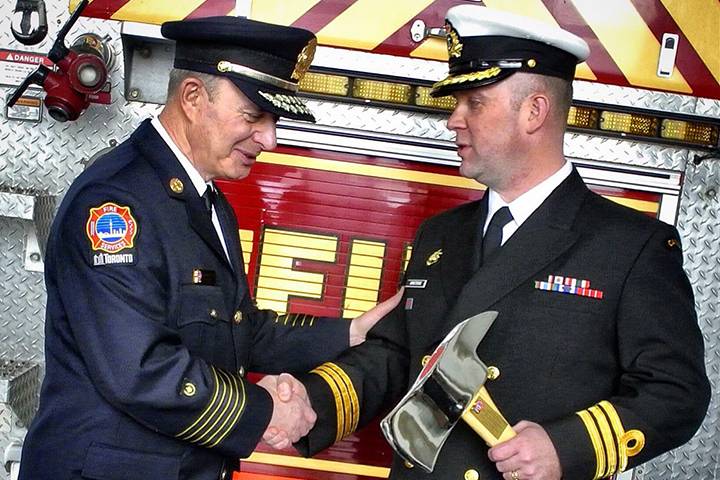 Former Toronto Fire Chief Jim Sales shakes hands with Commander Jason Armstrong of the HMCS Toronto after being presented with a ceremonial axe on February 6, 2015.