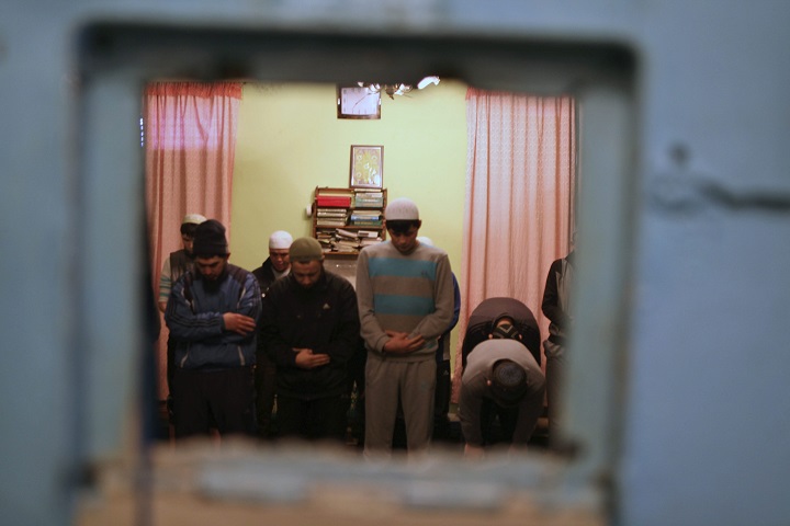 In this Thursday, Jan. 26, 2012 photo,  taken taken through a shutter in the prison cell door, inmates gather to pray in pre-trial detention center 1 in Bishkek, Kyrgyzstan. 