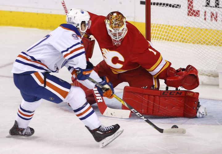 Edmonton Oilers' Connor McDavid, left, scores on Calgary Flames goalie Brian Elliott during first period NHL action in Calgary, Alta., Friday Oct. 14, 2016. 