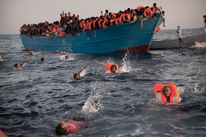 Migrants jump into the water from a crowded wooden boat as they are helped by members of an NGO during a rescue operation in the Mediterranean Sea north of Libya, Monday, Aug. 29, 2016. 