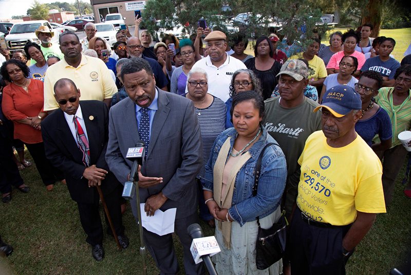 Derrick Johnson, left, president of the Mississippi NAACP, center left, talks to the media on behalf of Stacey Payton, center right, and Hollis Payton, behind his wife Stacey, in front of the Stone County Courthouse in Wiggins, Miss., Monday, Oct. 24, 2016. 