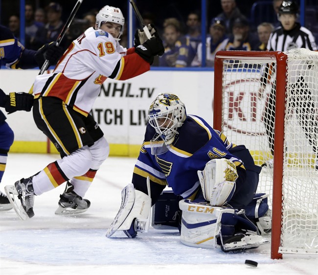 St. Louis Blues goalie Carter Hutton, right, deflects a puck as Calgary Flames' Matthew Tkachuk watches during the first period of an NHL hockey game Tuesday, Oct. 25, 2016, in St. Louis.