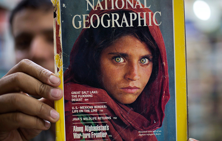 Pakistan's Inam Khan, owner of a book shop shows a copy of a magazine with the photograph of Afghan refugee woman Sharbat Gula, from his rare collection in Islamabad, Pakistan, Wednesday, Oct. 26, 2016. 