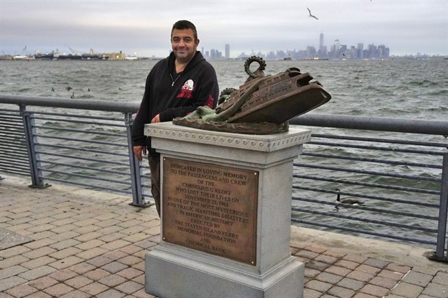 In this Sept. 29, 2016 photo, artist Joseph Reginella poses for a photo, in the Staten Island borough of New York, with the cast bronze faux monument dedicated to the memory of the victims of the steam ferry Cornelius G. Kolff, It took Reginella six months to execute his multi-layered project that includes the faux memorial, a sophisticated website complete with a documentary, a mocked-up newspaper articles and glossy fliers directing tourists to a phantom Staten Island Ferry Disaster Memorial Museum with small pieces of the wreckage on display _ some with "strange suction-cup-shaped marks.".