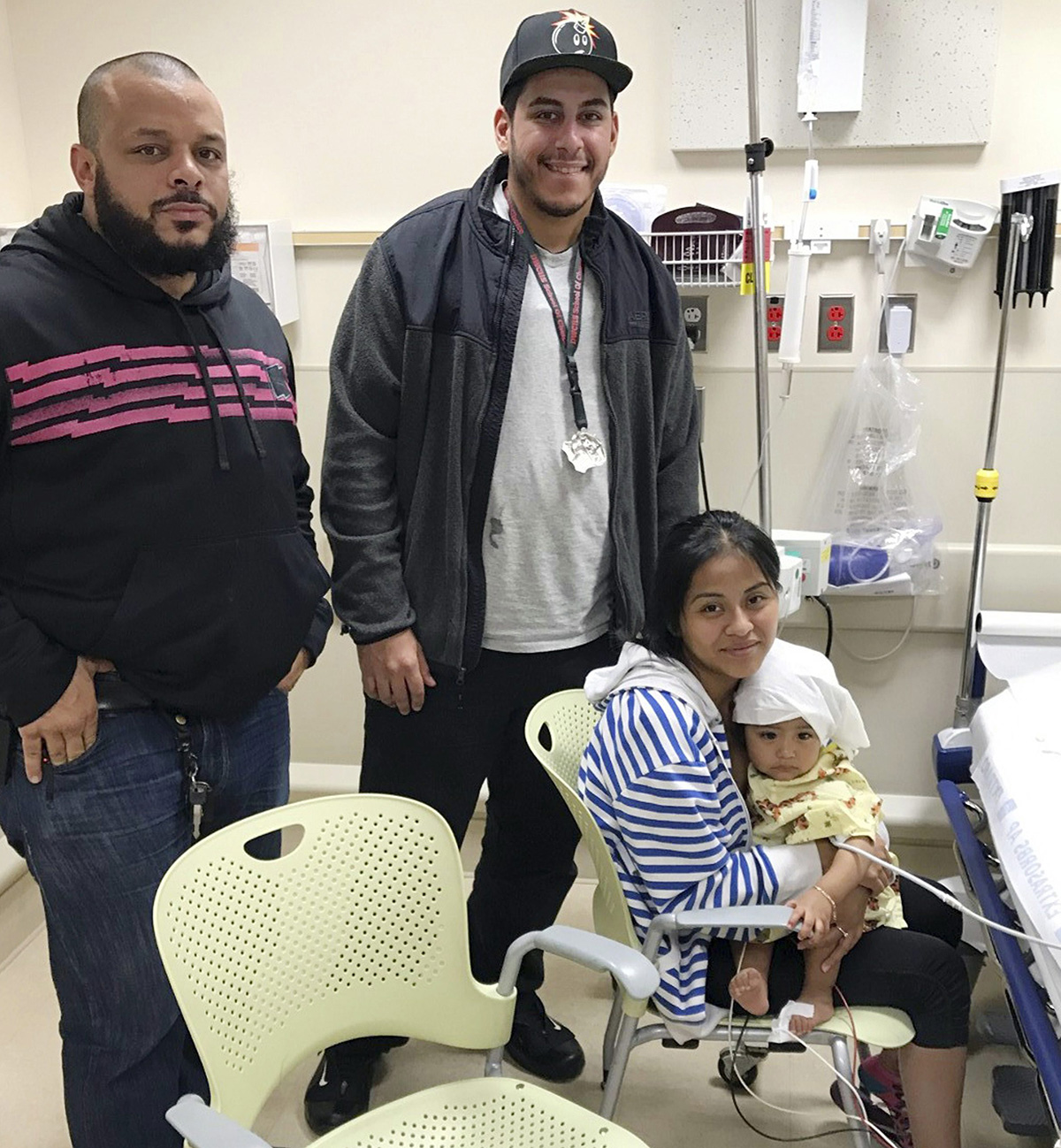 In this Oct. 14, 2016 photo released by the New York City Police Department, officers Felix Baez, left, and Giovanni Laguna pose for a photo with Liliana Benigno, and her one-year-old baby Ashley Delores, at Lincoln Hospital in The Bronx borough of New York.
