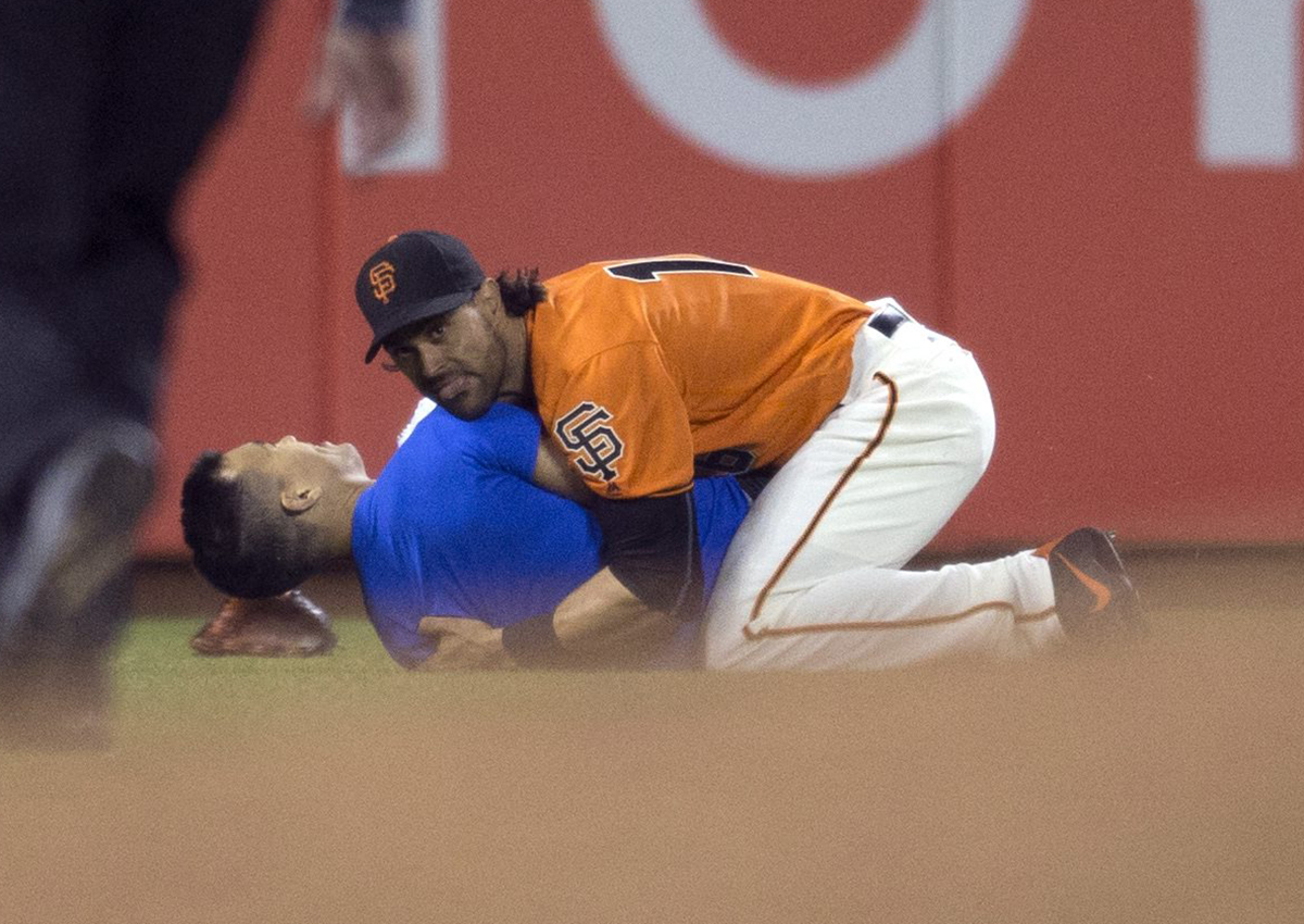 San Francisco Giants’ Angel Pagan ( holds down a man who ran onto the field during the fourth inning of the Giants' baseball game against the Los Angeles Dodgers, Friday, Sept. 30, 2016, in San Francisco. 