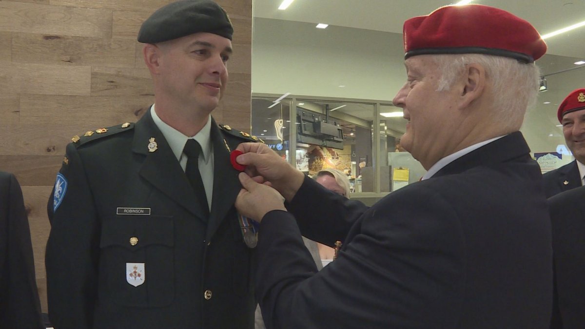 Hon. Lt. Col. Colin Robinson receives his poppy in a ceremonial pinning, Friday, October 28, 2016.