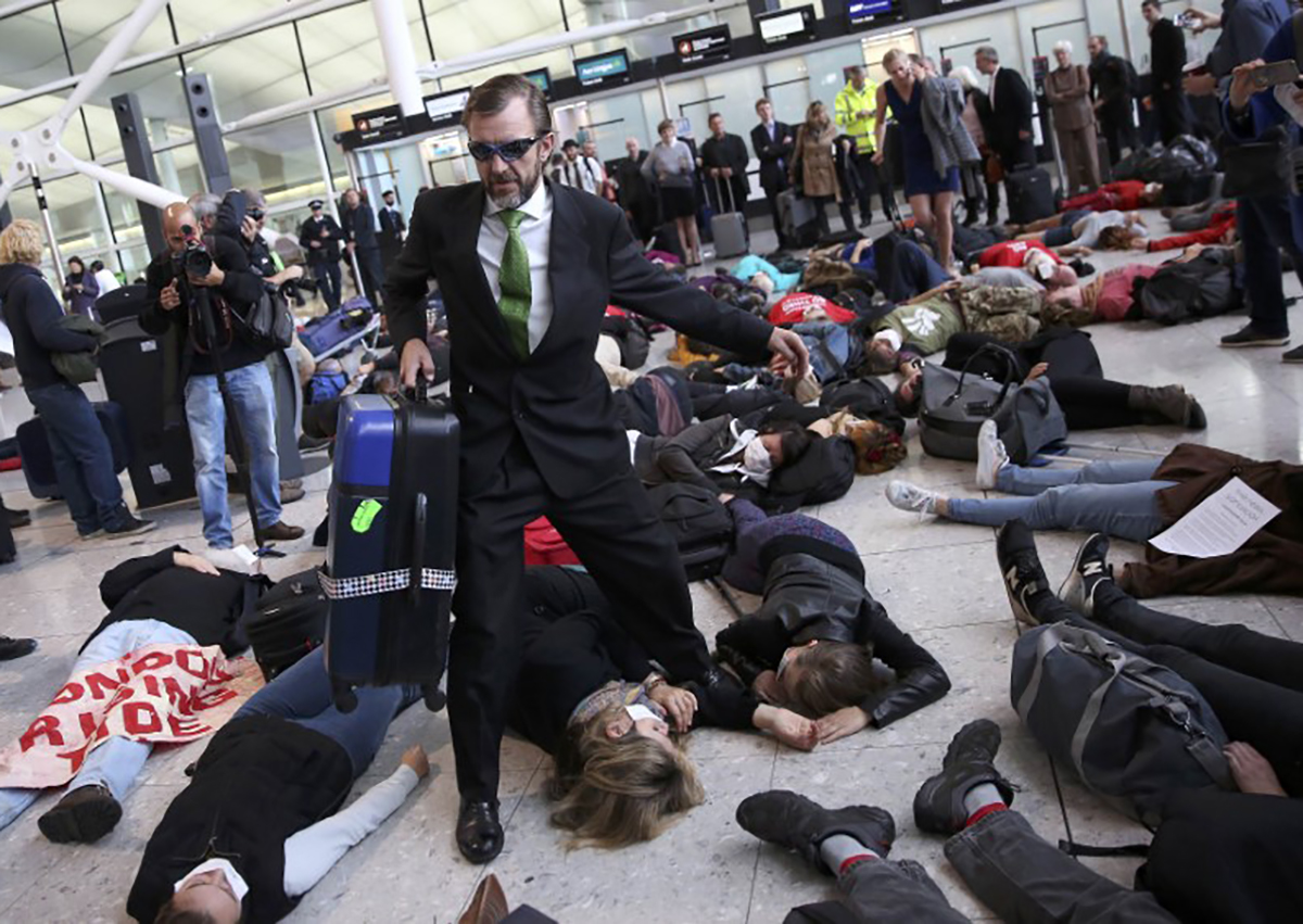 Climate activist group Reclaim the Power lie on the ground and carry luggage during a protest against airport expansion plans at Heathrow Airport in London, Britain October 1, 2016.