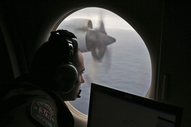 In this March 22, 2014 file photo, flight officer Rayan Gharazeddine scans the water in the southern Indian Ocean off Australia from a Royal Australian Air Force AP-3C Orion during a search for the missing Malaysia Airlines Flight MH370. A ship involved with the deep-sea sonar search for missing Malaysia Airlines Flight 370 is being fitted with equipment to examine several sonar contacts of interest on the remote seabed west of Australia, the Australian Transport Safety Bureau said on Wednesday, Oct. 19, 2016. 