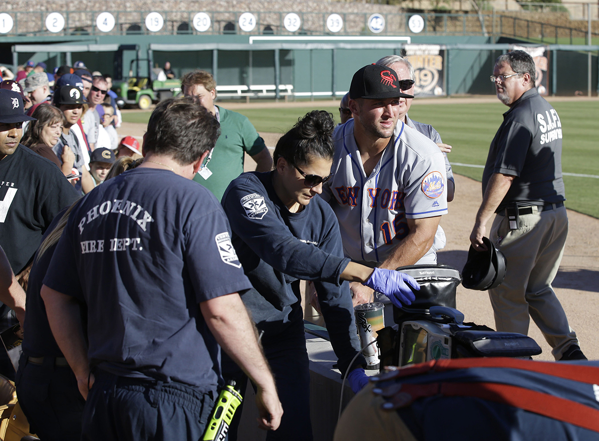 Scottsdale Scorpions outfielder Tim Tebow, center, comforts a fan, on ground, who was suffering a seizure, following Tebow's debut against the Glendale Desert Dogs in a baseball game Tuesday, Oct. 11, 2016, during the Arizona Fall League in Glendale, Ariz.