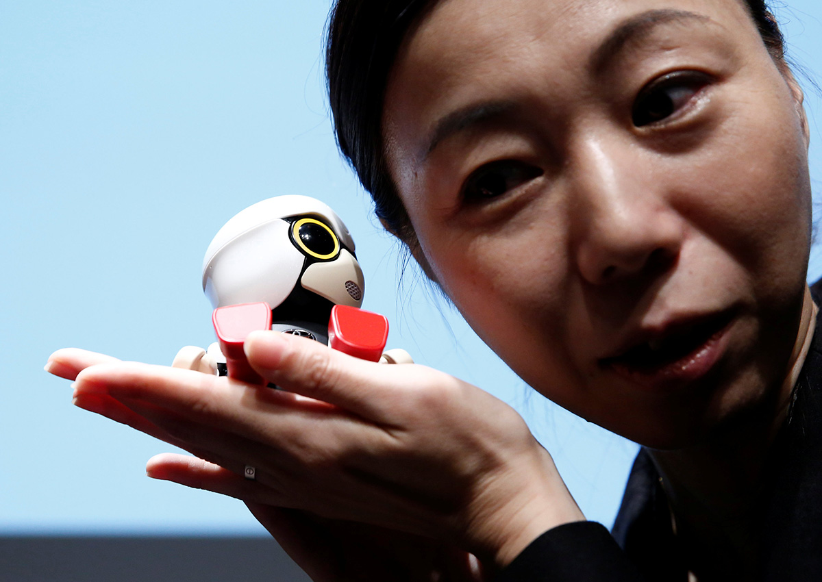 A staff member listens to Toyota Motor Corp's Kirobo Mini robot's voice as she poses with the robot after a news conference in Tokyo, Japan, September 27, 2016. Picture taken on September 27, 2016.
