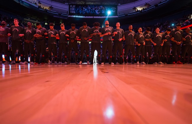 Toronto Raptors players lock arms during the singing of the national anthems before a pre-season NBA basketball game against the Golden State Warriors in Vancouver, B.C., on Saturday October 1, 2016.