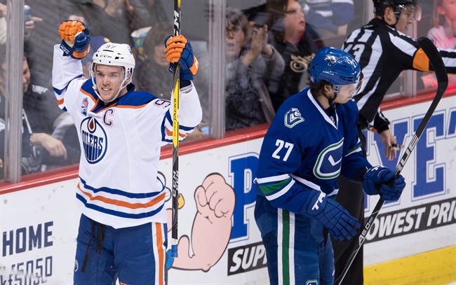 Edmonton Oilers' Connor McDavid, left, celebrates after scoring as Vancouver Canucks' Ben Hutton looks on during the second period of an NHL hockey game in Vancouver, B.C., on Friday October 28, 2016. 