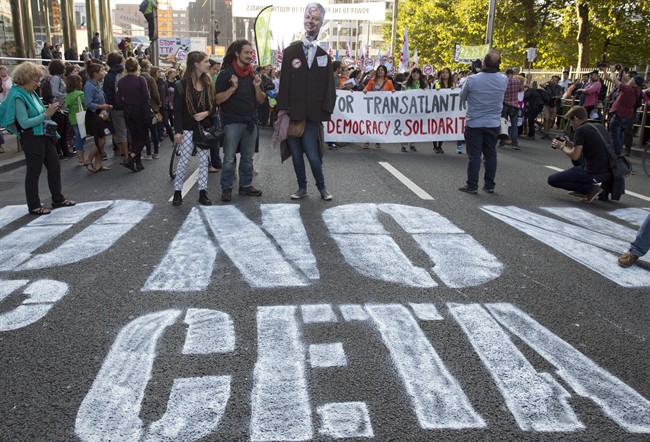 In this photo taken on Tuesday, Sept. 20, 2016, demonstrators walk over a spray painted sign on the street during a demonstration against international trade agreements in Brussels.