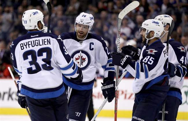 Winnipeg Jets' Dustin Byfuglien (33), Blake Wheeler (26), Mathieu Perreault (85) and Kyle Connor (41) celebrate after Wheeler scored against the Ottawa Senators during second period pre-season NHL hockey in Winnipeg, Monday, October 3, 2016.
