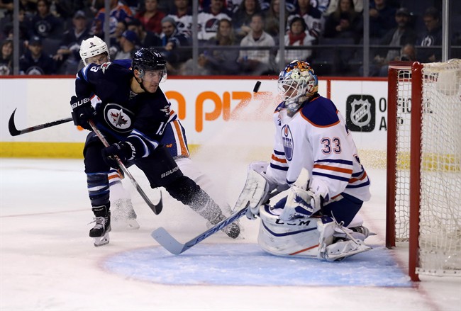 Winnipeg Jets' Brandon Tanev (13) fires the puck on Edmonton Oilers goaltender Cam Talbot (33) with Adam Larsson (6) trailing during second period pre-season NHL hockey in Winnipeg, Friday, September 30, 2016.