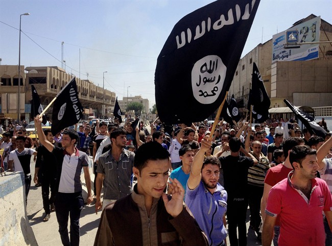FILE - In this June 16, 2014. file photo, demonstrators chant pro-Islamic State group slogans as they carry the group's flags in front of the provincial government headquarters in Mosul, Iraq.