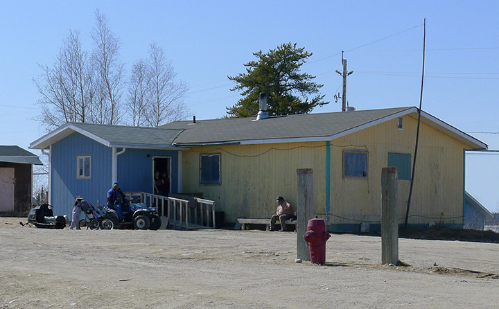 People sits outside a home in North Caribou Lake First Nation, 320 km north of Sioux Lookout, Ontario on Thursday April 12, 2012. 