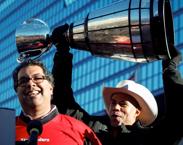 Calgary Stampeders Jon Cornish, right, lifts the Grey Cup as he listens to Calgary Mayor Naheed Nenshi during a rally celebrating the win in Calgary, Tuesday, Dec. 2, 2014.