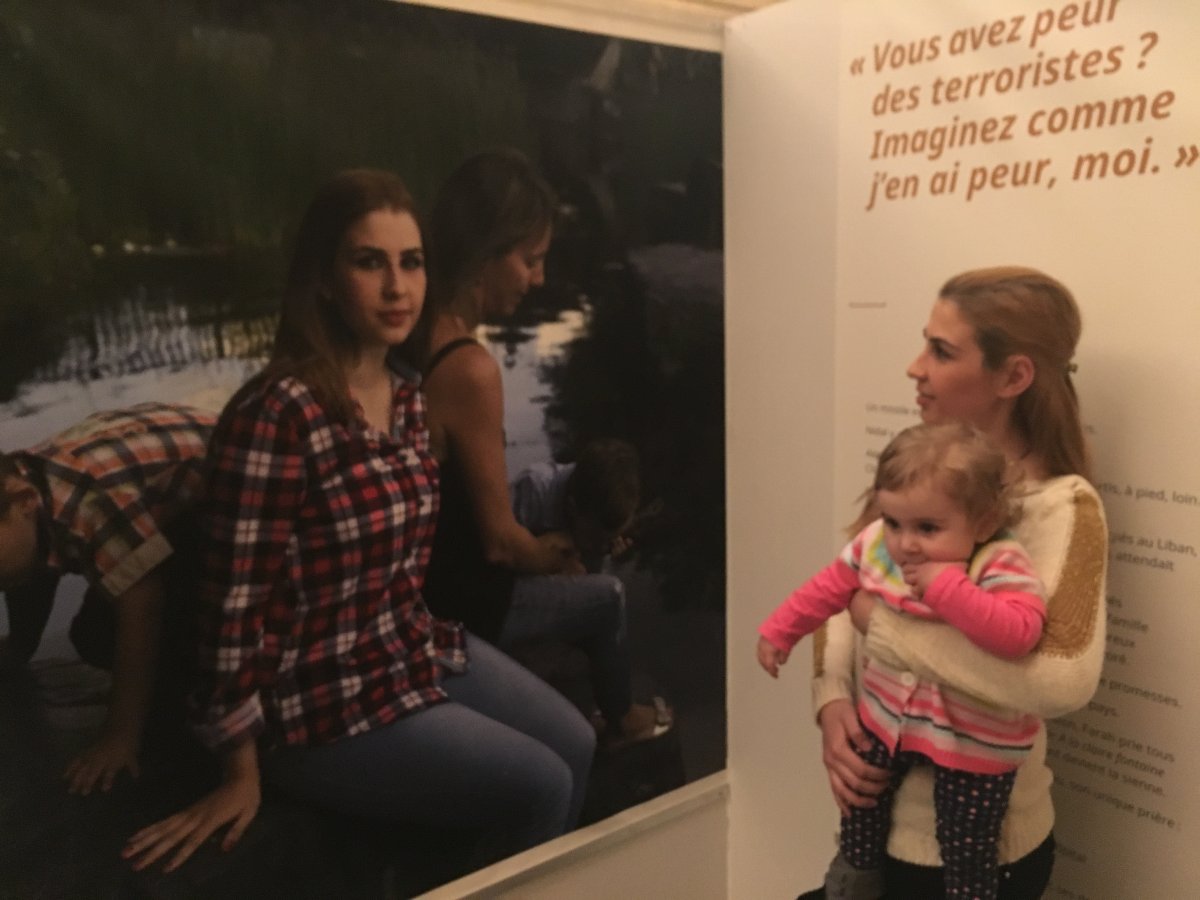 Reem looks at her photo during the exhibit "I'm not from Space" at City Hall while holding her baby girl. Wednesday November 09, 2016.