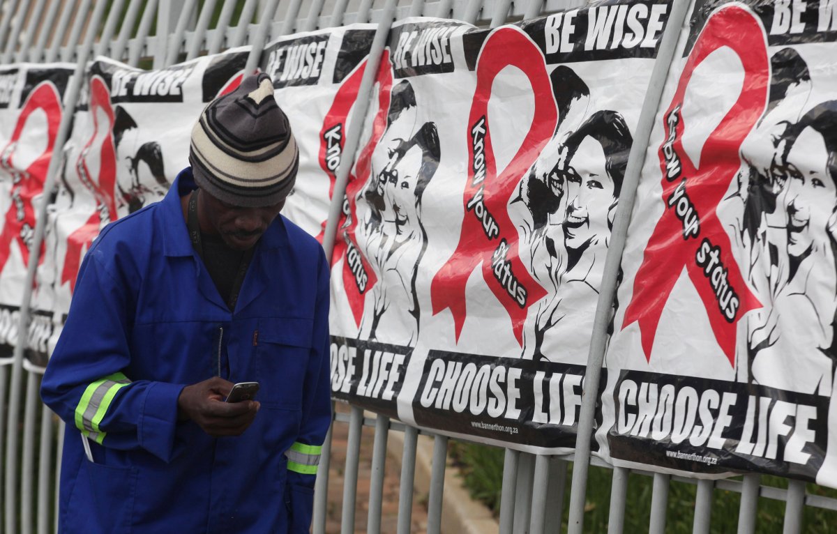  In this Dec. 1, 2014 file photo a man makes a call on a mobile phone as he passes World AIDS Day banners on the perimeter of an office building in Sandton, Johannesburg, South Africa. 