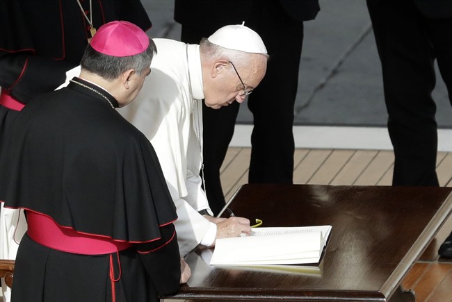 Pope Francis signs a letter after Mass at St. Peter's Basilica at the Vatican on Sunday, Nov. 20, 2016.