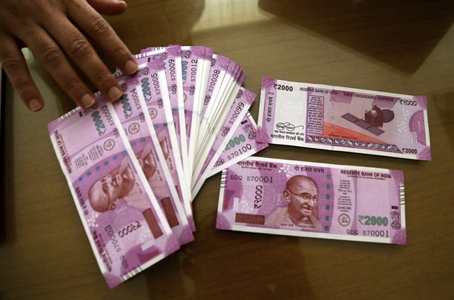 A bank official displays new Indian currency notes of 2000 rupees before disbursing to their clients in Bangalore, India, Thursday, Nov. 10, 2016. Delivering one of India's biggest-ever economic upsets, Prime Minister Narendra Modi this week declared the bulk of Indian currency notes no longer held any value and told anyone holding those bills to take them to banks. (AP Photo/Aijaz Rahi).