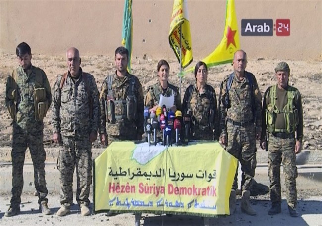 This frame grab from video provided by Arab 24 network, shows officials with the U.S.-backed Syria Democratic Forces at a press conference in Ein Issa in northern Syria.