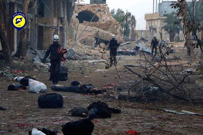 This photo provided by the Syrian Civil Defense White Helmets, which has been authenticated based on its contents and other AP reporting, shows workers pass by bodies after artillery fire struck the Jub al-Quba district in Aleppo, Syria, Wednesday, Nov. 30, 2016.