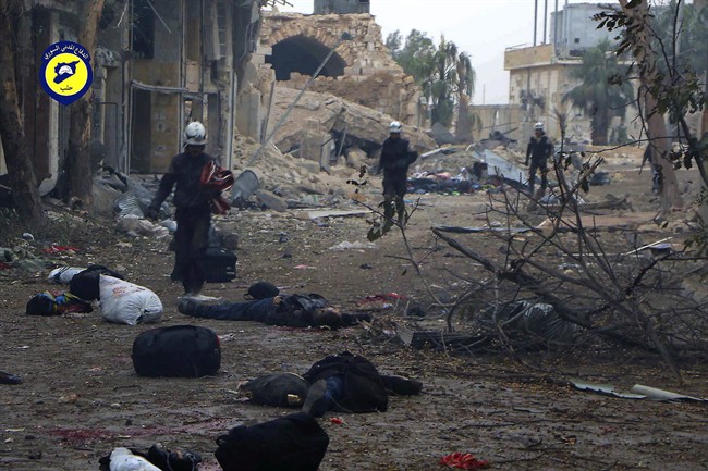 This photo provided by the Syrian Civil Defense White Helmets, which has been authenticated based on its contents and other AP reporting, shows Civil Defense workers pass by bodies after artillery fire struck the Jub al-Quba district in Aleppo, Syria, Wednesday, Nov. 30, 2016. Syrian activists say at least 21 people have been killed in an artillery barrage on a housing area for those displaced in rebel-held eastern Aleppo. (Syrian Civil Defense White Helmets via AP).