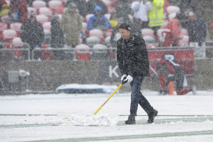 A worker helps to remove snow on the playing field before first half CFL eastern final action between the Ottawa RedBlacks and Edmonton Eskimos, in Ottawa on Sunday, November 20, 2016. 