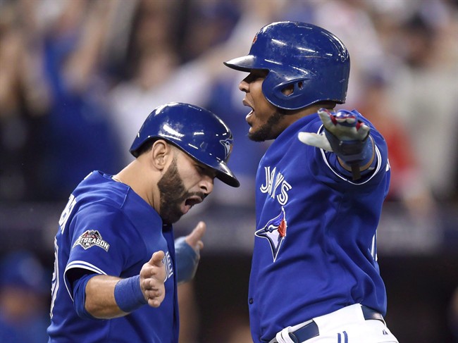 Toronto Blue Jays' Jose Bautista, left, and Edwin Encarnacion celebrate after scoring on a three-run double by Troy Tulowitzki during sixth inning game five American League Championship Series baseball action against the Kansas City Royals in Toronto on Wednesday, Oct. 21, 2015.