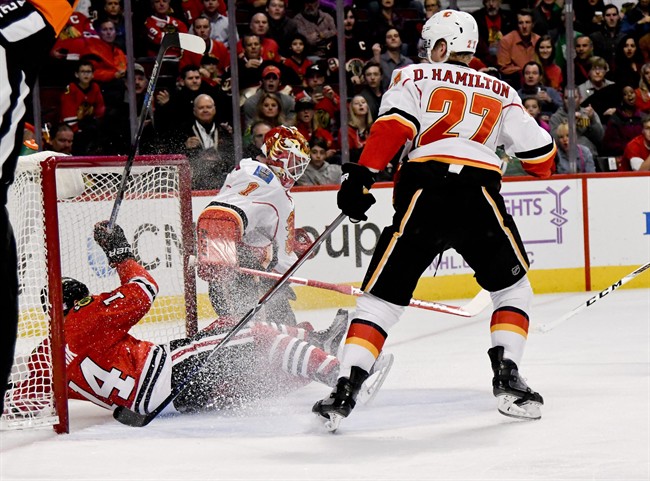 Chicago Blackhawks' Richard Panik, left, slides into the goal as Calgary Flames' Dougie Hamilton (27) and goalie Brian Elliott (1) watch during the first period of an NHL hockey game Tuesday Nov. 1, 2016, in Chicago.