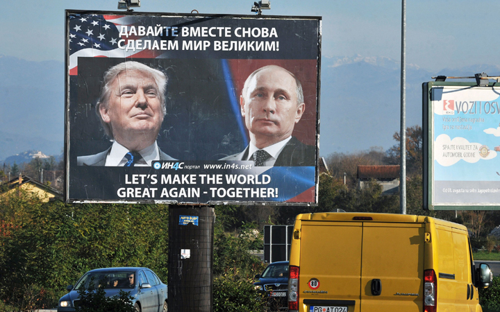 Cars pass by a billboard showing US President-elect Donald Trump and Russian President Vladimir Putin in the town of Danilovgrad on November 16, 2016. 