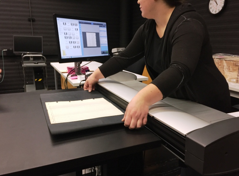 An employee at Library and Archives Canada uses a large-format scanner.