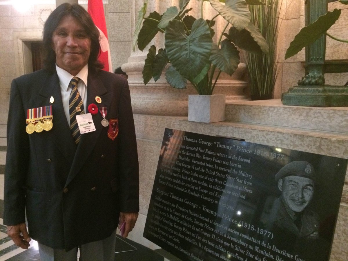 Tommy Prince Jr. poses beside a plaque honouring his father's wartime service.