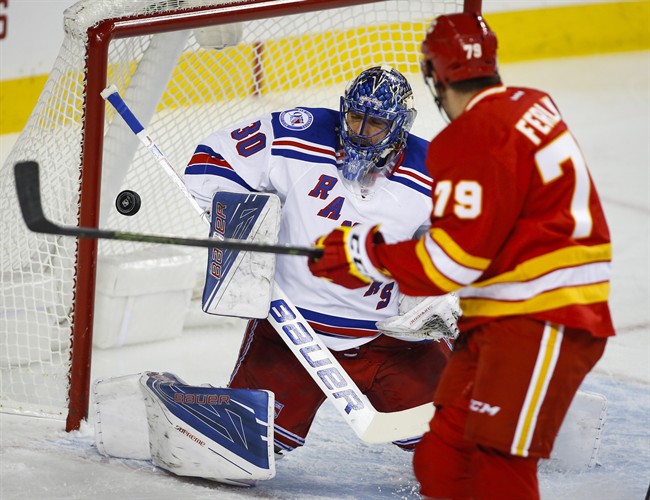 New York Rangers goalie Henrik Lundqvist, left, from Sweden, makes a save as Calgary Flames' Micheal Ferland looks on during first period NHL hockey action in Calgary, Saturday, Nov. 12, 2016.