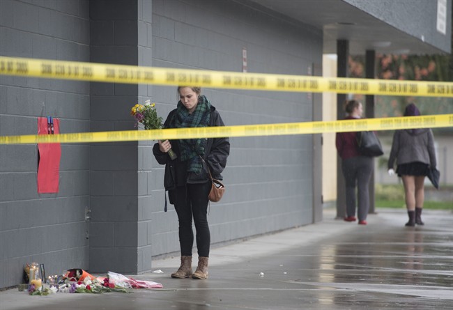 A girl arrives to lay flowers at a makeshift memorial outside Abbotsford Secondary School in in Abbotsford, B.C., Wednesday, Nov. 2, 2016. Two students were stabbed at the school Tuesday, leaving one dead and one in hospital. THE CANADIAN PRESS/Jonathan Hayward.