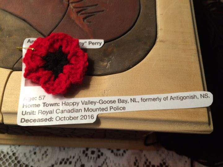 One of the crocheted poppies attached to some information about a fallen soldier.