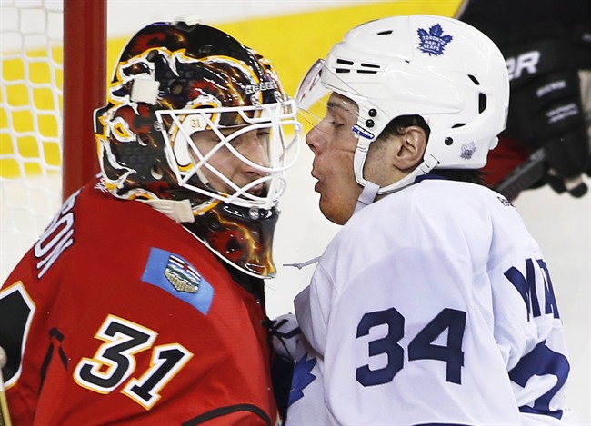 Toronto Maple Leafs' Auston Matthews, right, comes face-to-mask in the crease with Calgary Flames' goalie Chad Johnson during second period NHL action in Calgary, Alta., Wednesday, Nov. 30, 2016. 