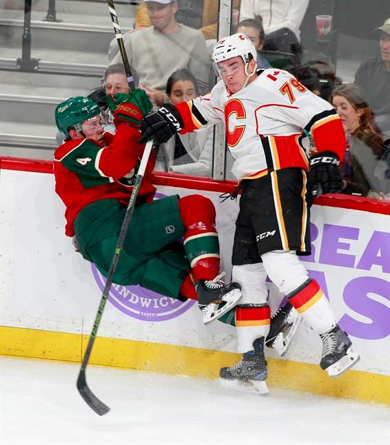 Minnesota Wild defenseman Mike Reilly (4) is checked off the ice by Calgary Flames left wing Micheal Ferland (79) during the first period of an NHL hockey game, Tuesday, Nov. 15, 2016, in St. Paul, Minn. 