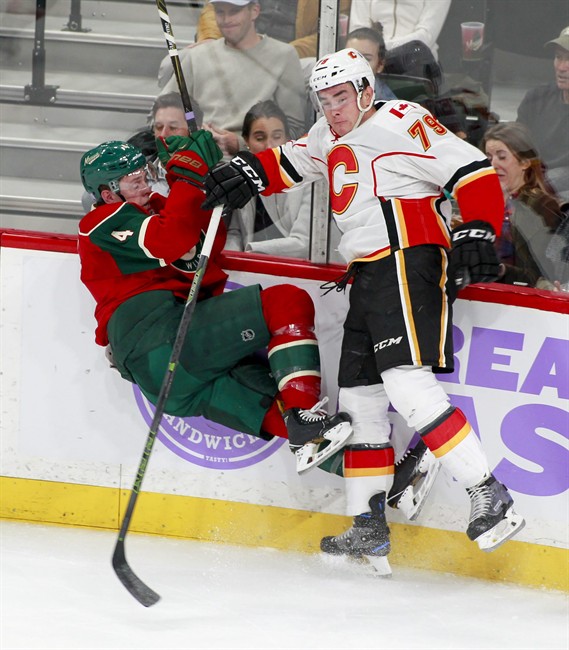 Minnesota Wild defenseman Mike Reilly (4) is checked off the ice by Calgary Flames left wing Micheal Ferland (79) during the first period of an NHL hockey game, Tuesday, Nov. 15, 2016, in St. Paul, Minn. 