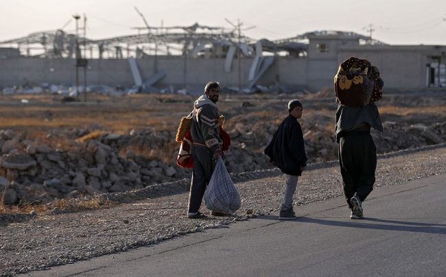 Displaced Iraqis who fled Mosul walk on a road in Bartalla, east of Mosul. 
